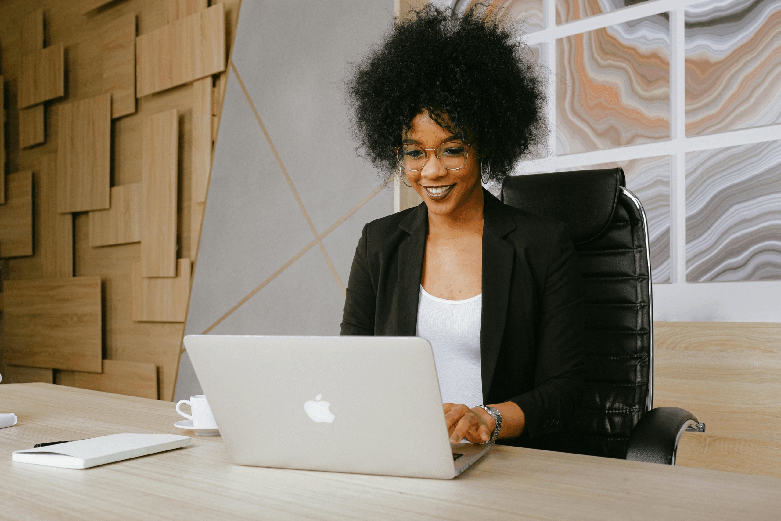 A Black woman sitting at a desk, focused on her computer screen.